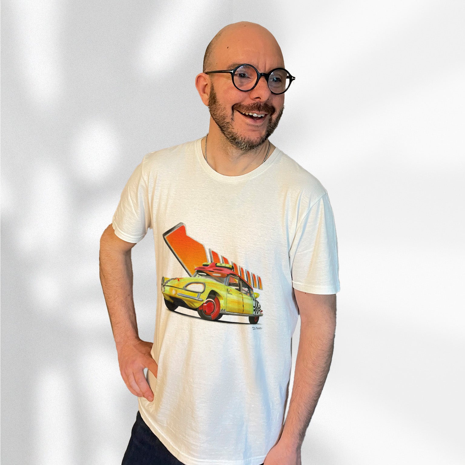 T-shirt blanc avec la DS "Hep Taxi" et la flèche orange mythique de Retour vers le Futur dessinés au milieu, porté par Matthieu Deloffre