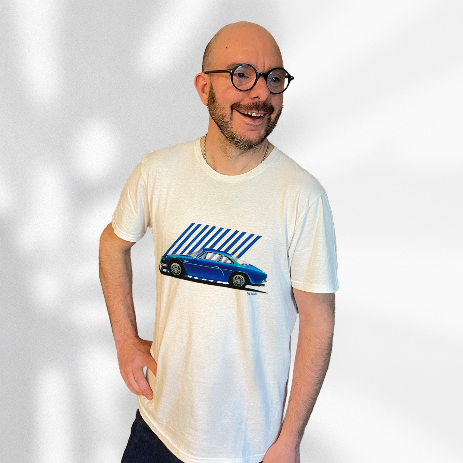 T-shirt blanc avec une superbe Alpine A110 bleue ancien modèle dessiné au milieu, porté par Matthieu Deloffre