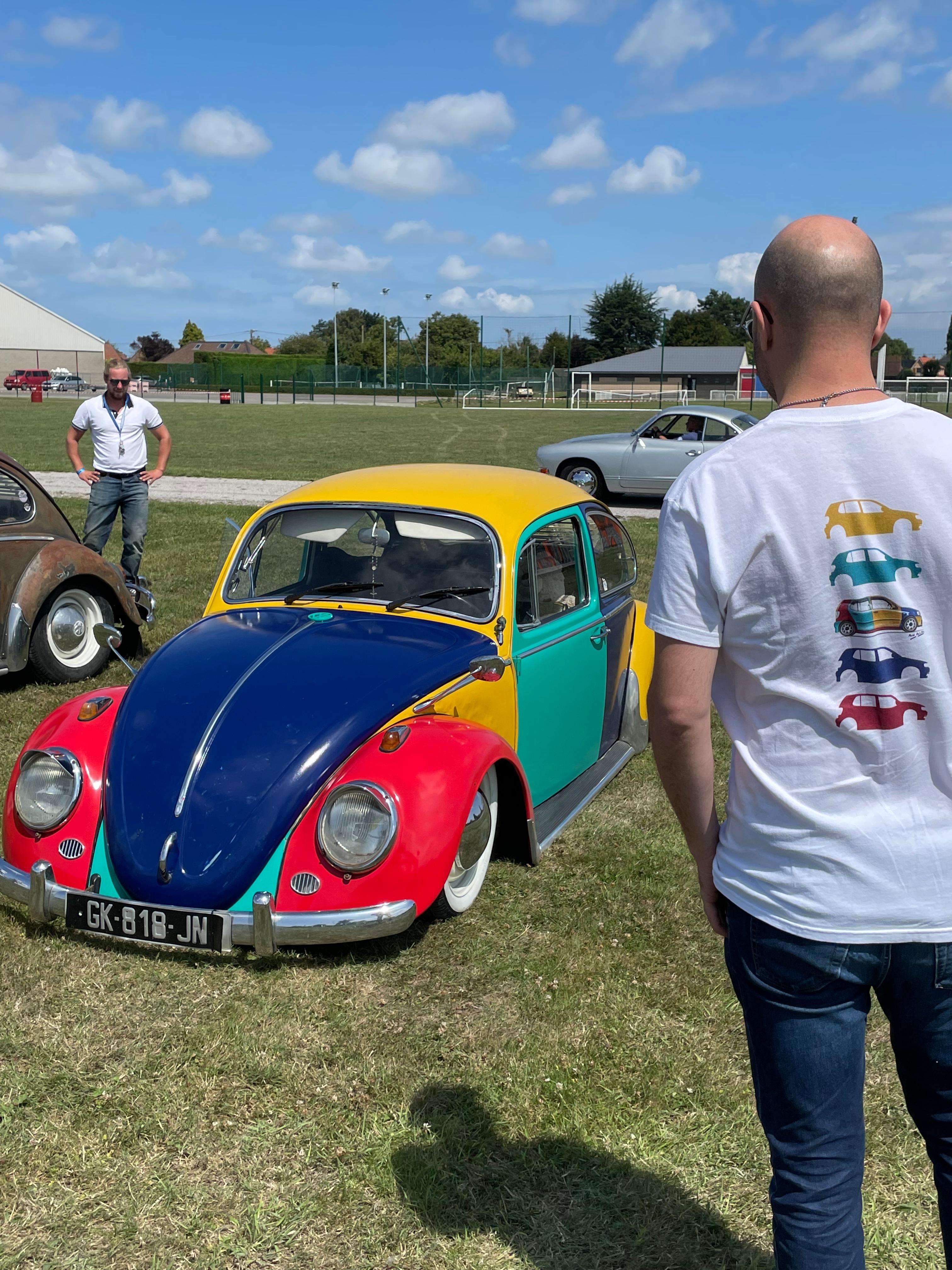 Matthieu Deloffre avec le t-shirt Volkswagen Harlequin Décomposée, de dos, dans un rassemblement Volkswagen