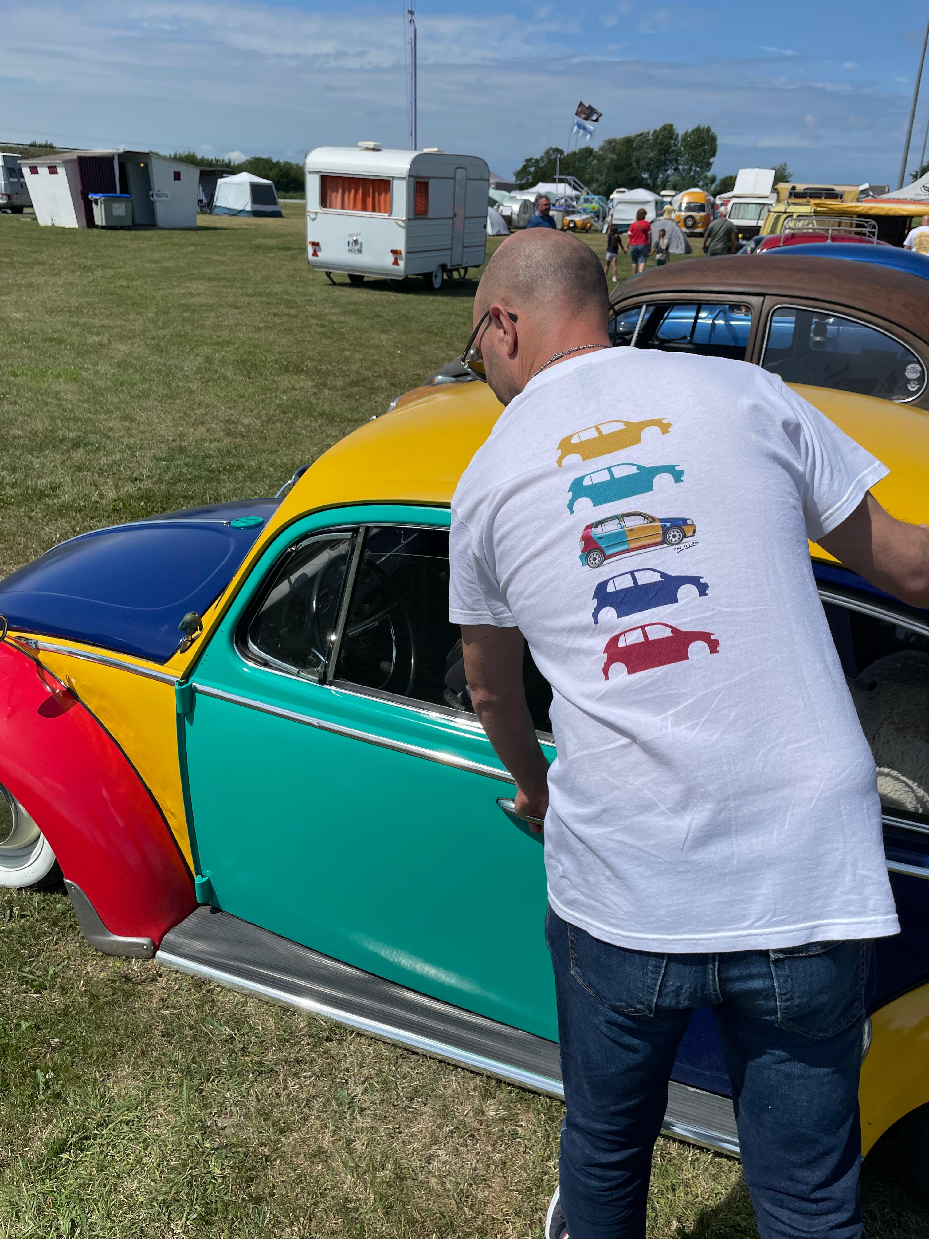 Matthieu Deloffre avec le t-shirt Volkswagen Harlequin Décomposée, de dos, dans un rassemblement Volkswagen
