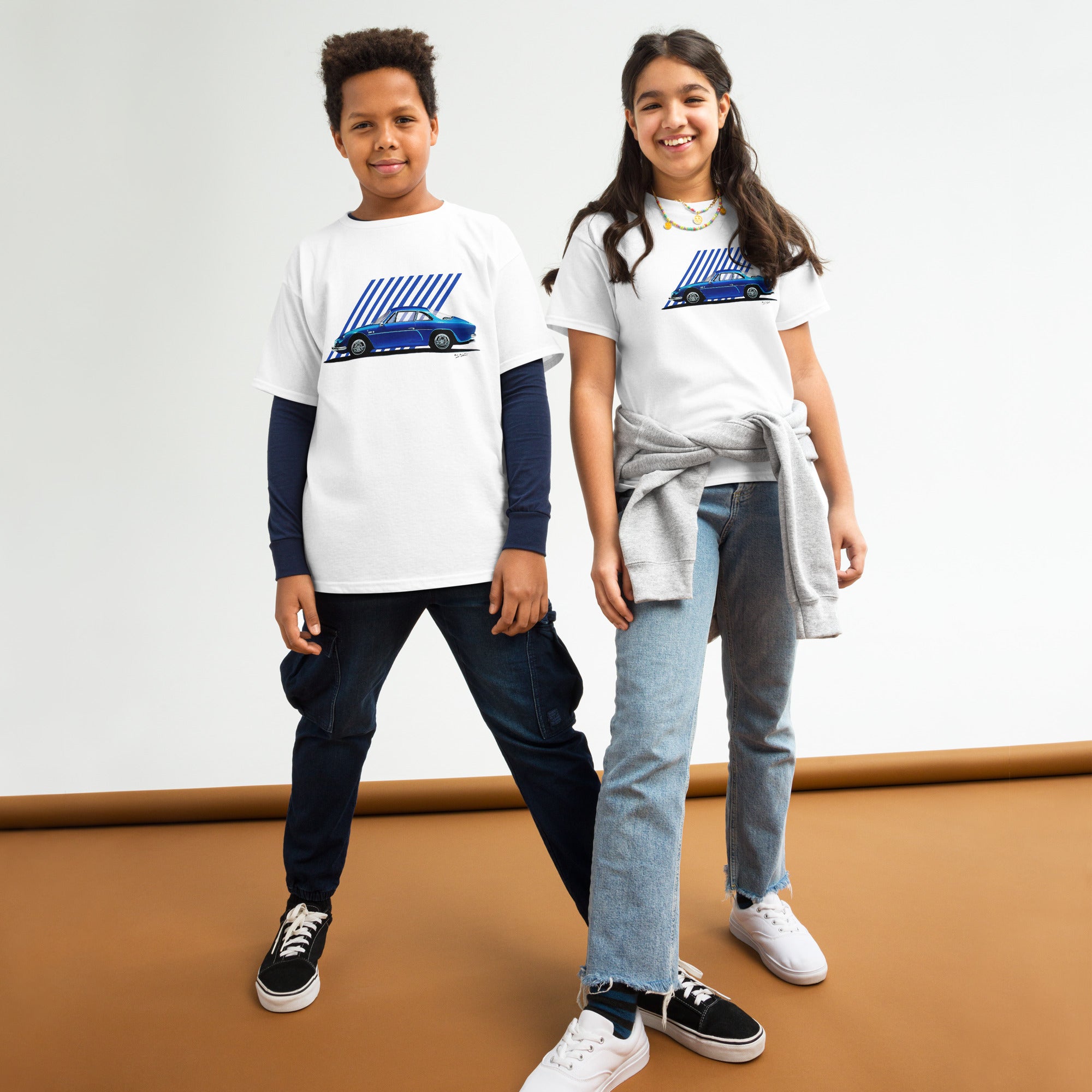 T-shirt blanc pour enfant avec une Alpine A110 bleu électrique illustrée au milieu, porté par des enfants